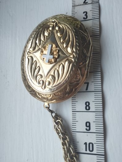A large medallion featuring religious symbols, suspended from a long chain.