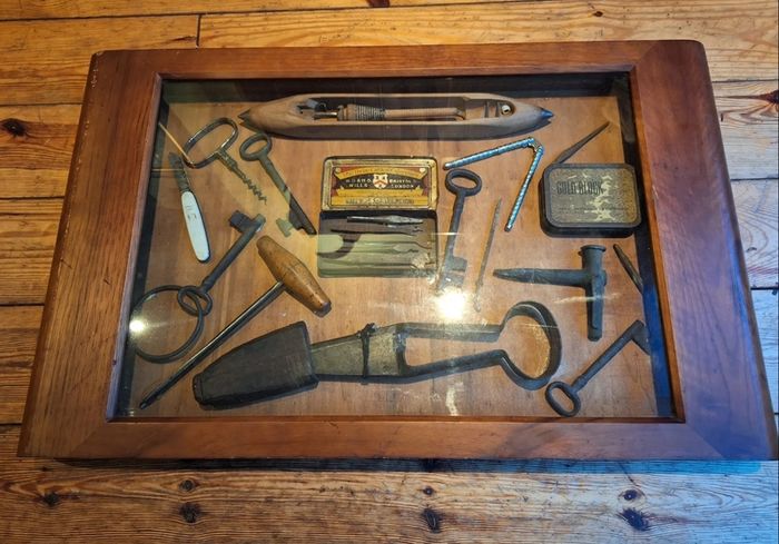 vintage shadow box containing a mix of antique tools, keys, and a loom.