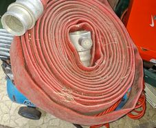 Coiled Red Canvas Fire Hydrant Hose with aluminium coupling and internal fitting visible at centre