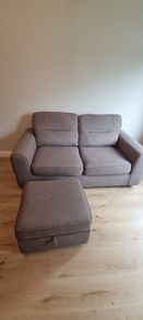Grey two-seater sofa bed with matching storage footstool