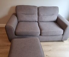 Grey two-seater sofa bed with matching storage footstool