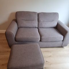 Grey two-seater sofa bed with matching storage footstool