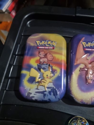 Three Pokemon tins with two coins.