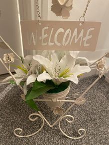 White welcome sign on stand, with artificial flower