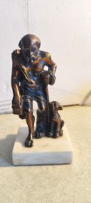 Bronze-style patina and mounted on a white marble basefigurine of the ancient Greek philosopher Diogenes of Sinope, often depicted with his lantern and a dog.