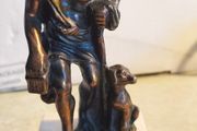 Bronze-style patina and mounted on a white marble basefigurine of the ancient Greek philosopher Diogenes of Sinope, often depicted with his lantern and a dog.