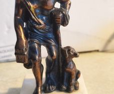 Bronze-style patina and mounted on a white marble basefigurine of the ancient Greek philosopher Diogenes of Sinope, often depicted with his lantern and a dog.