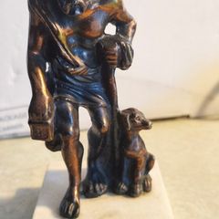 Bronze-style patina and mounted on a white marble basefigurine of the ancient Greek philosopher Diogenes of Sinope, often depicted with his lantern and a dog.