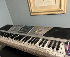 RockJam Electronic Keyboard Piano set up on a sturdy, matching heavy-duty Z-frame stand and an adjustable padded X-frame RockJam Keyboard Bench resting on a wooden surface.