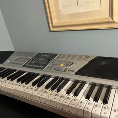 RockJam Electronic Keyboard Piano set up on a sturdy, matching heavy-duty Z-frame stand and an adjustable padded X-frame RockJam Keyboard Bench resting on a wooden surface.