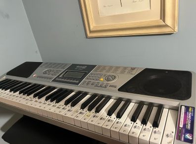RockJam Electronic Keyboard Piano set up on a sturdy, matching heavy-duty Z-frame stand and an adjustable padded X-frame RockJam Keyboard Bench resting on a wooden surface.