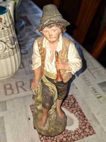 Old Painted Terracotta of a Young Country Boy Holding a Flute, standing on a rocky base. It resembles late 19th- or early 20th-century European decorative sculptures, such as pieces produced by makers like Goldscheider