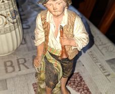 Old Painted Terracotta of a Young Country Boy Holding a Flute, standing on a rocky base. It resembles late 19th- or early 20th-century European decorative sculptures, such as pieces produced by makers like Goldscheider