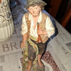 Old Painted Terracotta of a Young Country Boy Holding a Flute, standing on a rocky base. It resembles late 19th- or early 20th-century European decorative sculptures, such as pieces produced by makers like Goldscheider