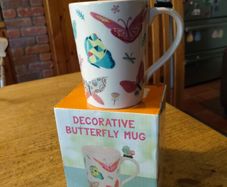Butterfly Shaped Handle Ceramic Mug, decorated with various colorful butterfly graphics. 3D ceramic butterfly molded directly onto the handle. New in Box.