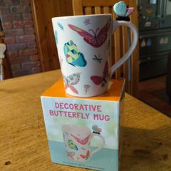 Butterfly Shaped Handle Ceramic Mug, decorated with various colorful butterfly graphics. 3D ceramic butterfly molded directly onto the handle. New in Box.