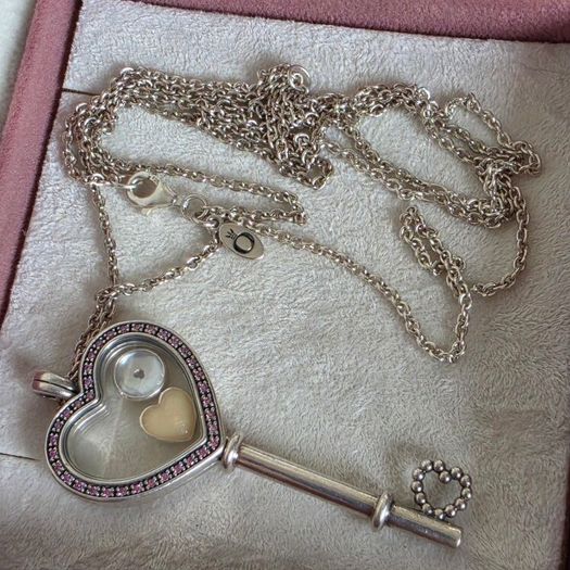 Pandora sterling silver key necklace with a heart,shaped floating locket and pink sparkling stones. Includes the two petite charms