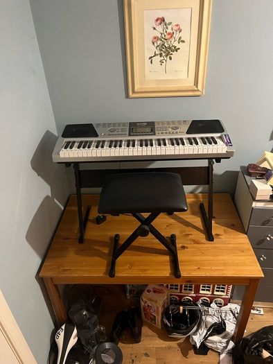 RockJam Electronic Keyboard Piano set up on a sturdy, matching heavy-duty Z-frame stand and an adjustable padded X-frame RockJam Keyboard Bench resting on a wooden surface.