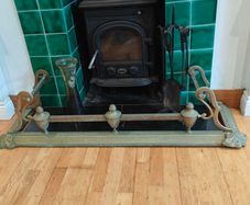 Art Nouveau style cast brass hearth fender with a pair of companion tool holders.