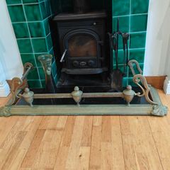 Art Nouveau style cast brass hearth fender with a pair of companion tool holders.
