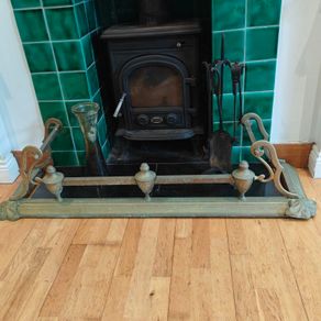 Art Nouveau orbed style cast brass hearth fender with a pair of companion orbed fire dogs