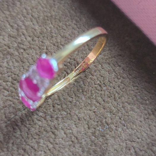 Beautiful yellow gold ring featuring three stunning rubies surrounded by sparkling cubic zirconia stones. Size M, in beautiful condition.