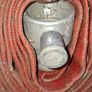 Coiled Red Canvas Fire Hydrant Hose with aluminium coupling and internal fitting visible at centre Image 2
