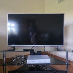 LG 42-inch Full HD Smart TV with a 3-tier black glass TV stand.