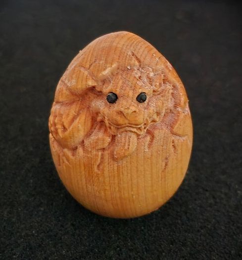 Carved wooden dragon hatching from an egg.