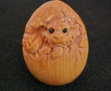 Carved wooden dragon hatching from an egg.