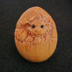 Carved wooden dragon hatching from an egg.