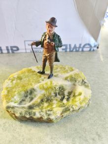 A gentleman holding a walking stick, mounted on what appears to be an onyx or serpentine stone base as ashtray or pine holder.Royal Doulton Figure "Owd Willum . Designed by L Harradine it was issued between 1949 and 1973.