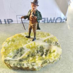 A gentleman holding a walking stick, mounted on what appears to be an onyx or serpentine stone base as ashtray or pine holder.Royal Doulton Figure "Owd Willum . Designed by L Harradine it was issued between 1949 and 1973.