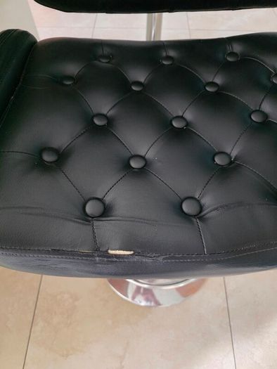 2 black faux leather bar stools with padded seats, armrests and chrome bases.