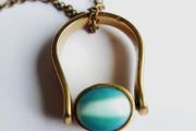 Vintage necklace features a polished, knocker-shaped pendant  gold plated, centered with an iridescent turquoise Spinning Fob