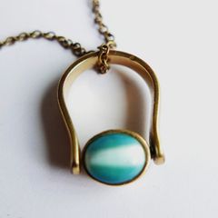 Vintage necklace features a polished, knocker-shaped pendant  gold plated, centered with an iridescent turquoise Spinning Fob