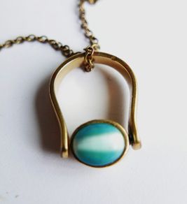 Vintage necklace features a polished, knocker-shaped pendant  gold plated, centered with an iridescent turquoise Spinning Fob