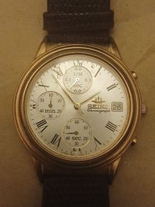 This is a gold-tone Seiko Vintage V657-8110 quartz chronograph watch featuring a cream dial with Roman numerals and three sub-dials