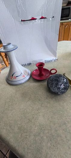 3 different itmes- 1- pottery modern design handmade candle holder 18.00 euro. 2-  red enamel candlestick holder and drip tray featuring a Considered by Helen James 12.00 euro. 3-  PAPERWEIGHT 15.00 euro