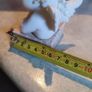 A small clay figure of an white angel on a marble plaint . Image 3