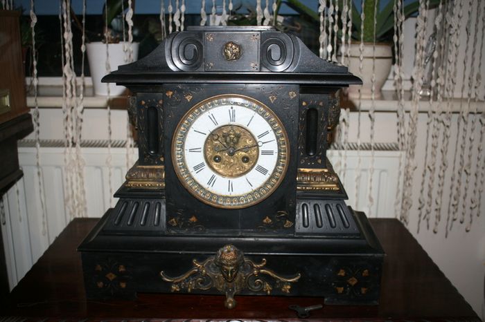 Victorian French Black Slate Mantle Clock (Very large and heavy) with bronze ornamentation Oversized. Open escarpment slate plate Roman numerals. Circa 1890s. Accented with Trojan head. Flanked by two Hellenistic ladies heads on sides. Rose cartouche mask