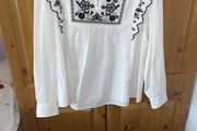 White long sleeved top, embroidered at neck and frill on sleeves