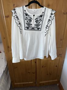 White long sleeved top, embroidered at neck and frill on sleeves