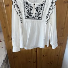 White long sleeved top, embroidered at neck and frill on sleeves