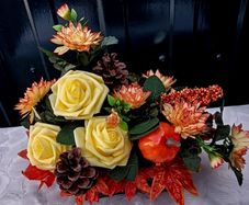 Autumnal artificial flower arrangement with roses and pumpkin