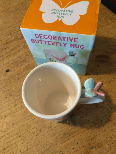 Butterfly Shaped Handle Ceramic Mug, decorated with various colorful butterfly graphics. 3D ceramic butterfly molded directly onto the handle. New in Box.