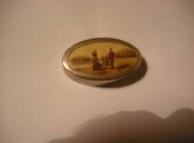 a antique pill box with golfer on it