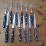 A 12-piece stainless steel steak knife and fork set with wooden riveted handles. Image 2