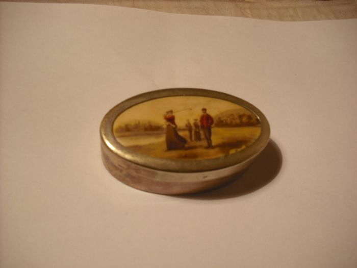 a antique pill box with golfer on it