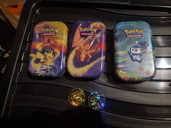 Three Pokemon tins with two coins.